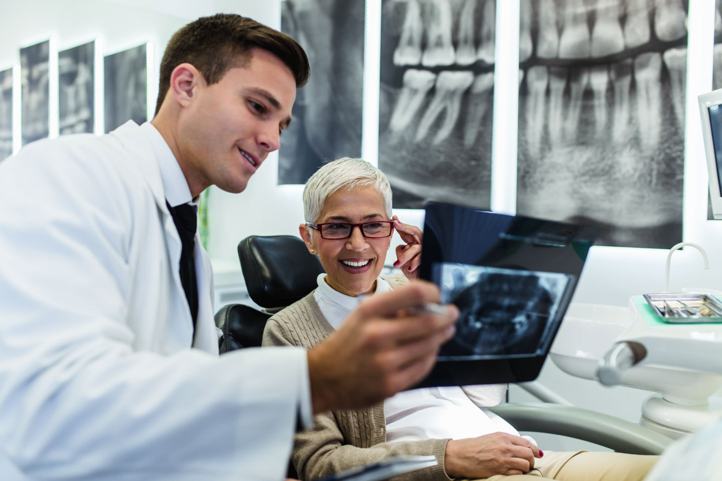 Handsome dentist looking at x-ray image of his senior woman pati dentist looking at x-ray image of his senior woman